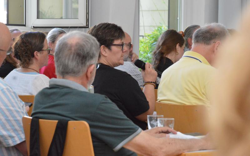 Ehrenamtliche Person spricht im Plenum bei der Veranstaltung ins Mikrofon